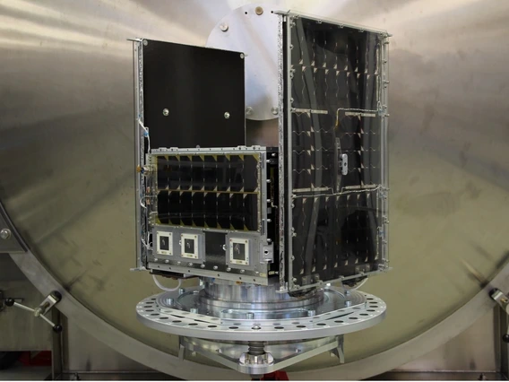 The completed spacecraft bus for the NASA Aspera mission, sitting on a table. Large solar panels provide the satellite with power. 
